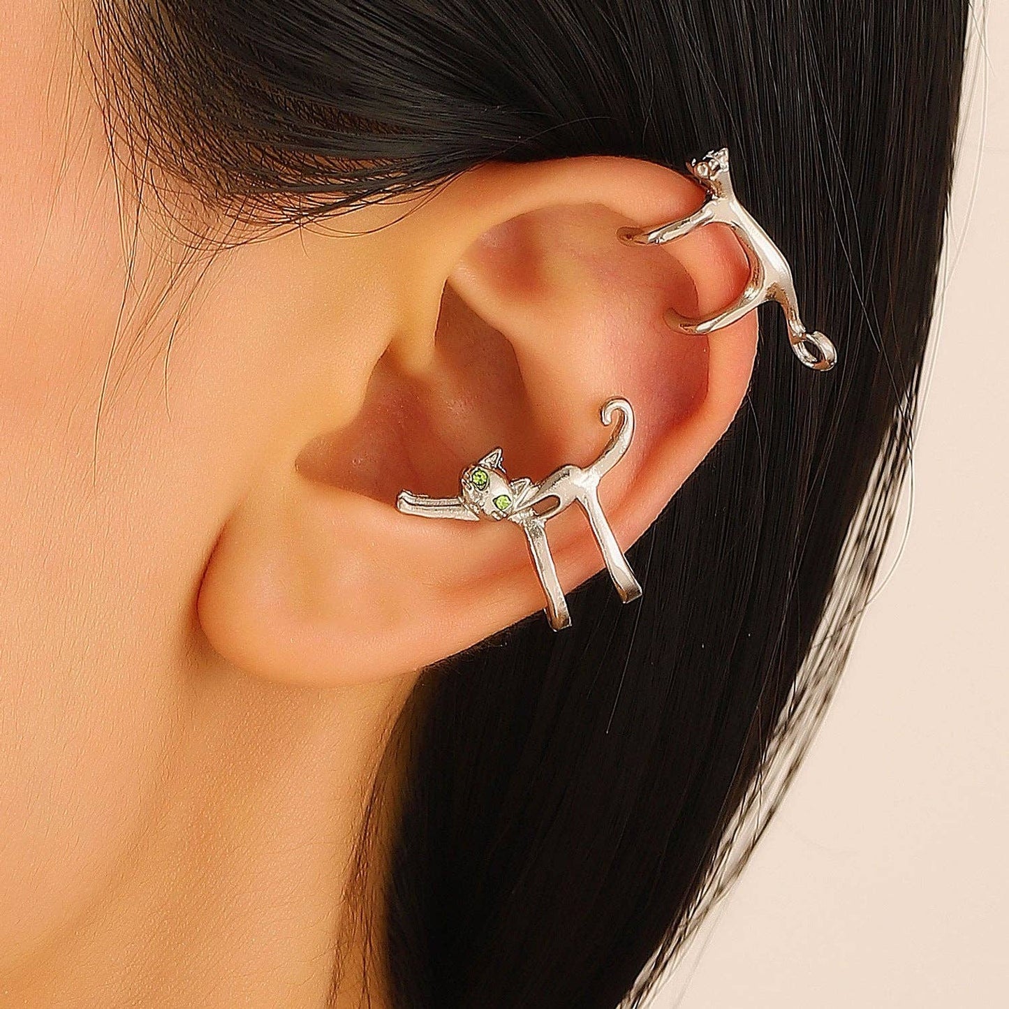 Silver cat-shaped earring worn on an ear with a neutral background