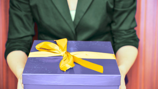 Woman holding a blue gift box with a yellow ribbon
