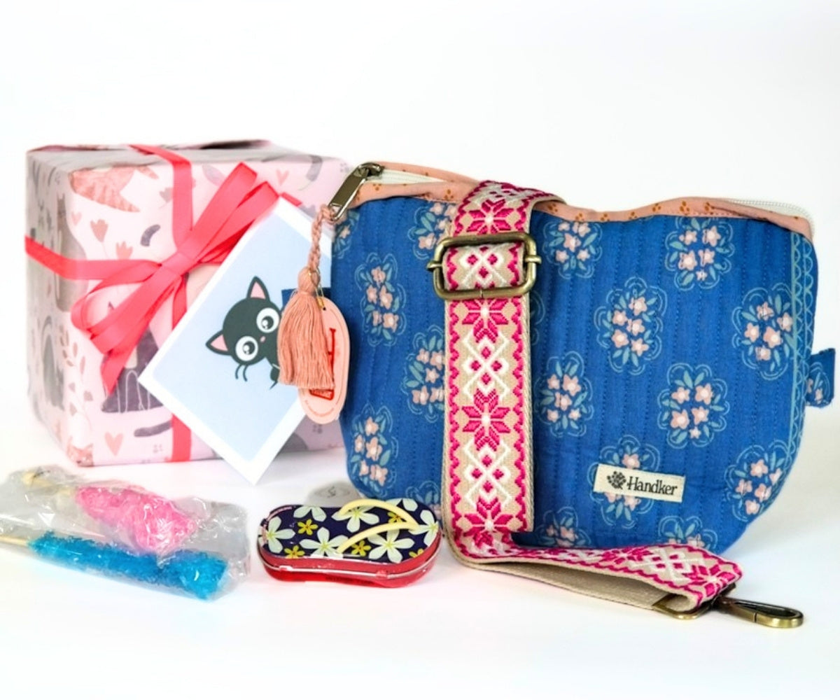 Colorful handbag with floral strap, flipflop mints tin, rock candy sticks and floral-patterned gift box on a white background