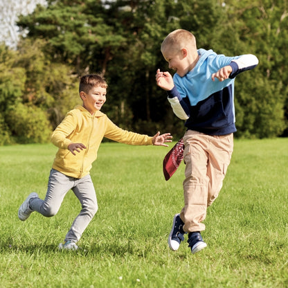 Two children running outdoors while using a red bandana during an active group game.
