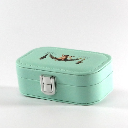 Miniature teal jewelry box with a button closure and a cupid on a floral garland, pictured from the side. 