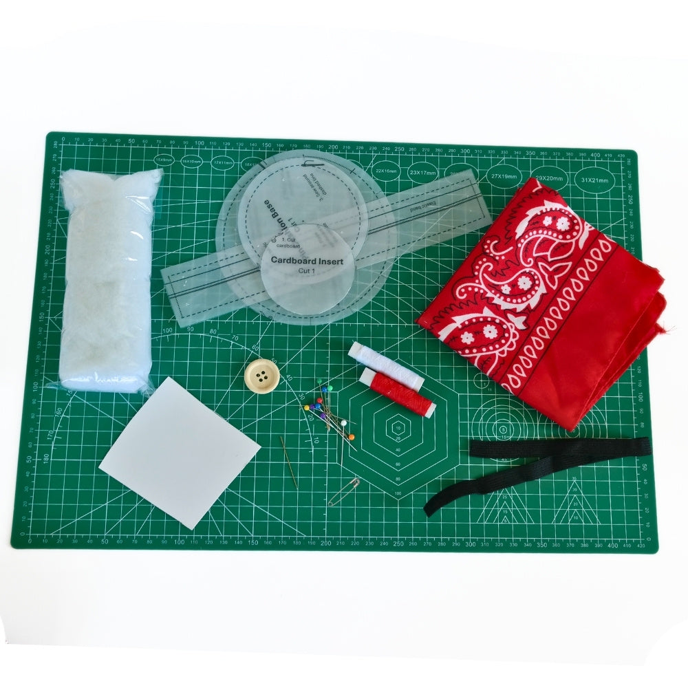 Lifestyle image of flower pin cushion wristband kit materials with bandana fabric, pattern pieces, stuffing, elastic, button, pins, needle, and thread.