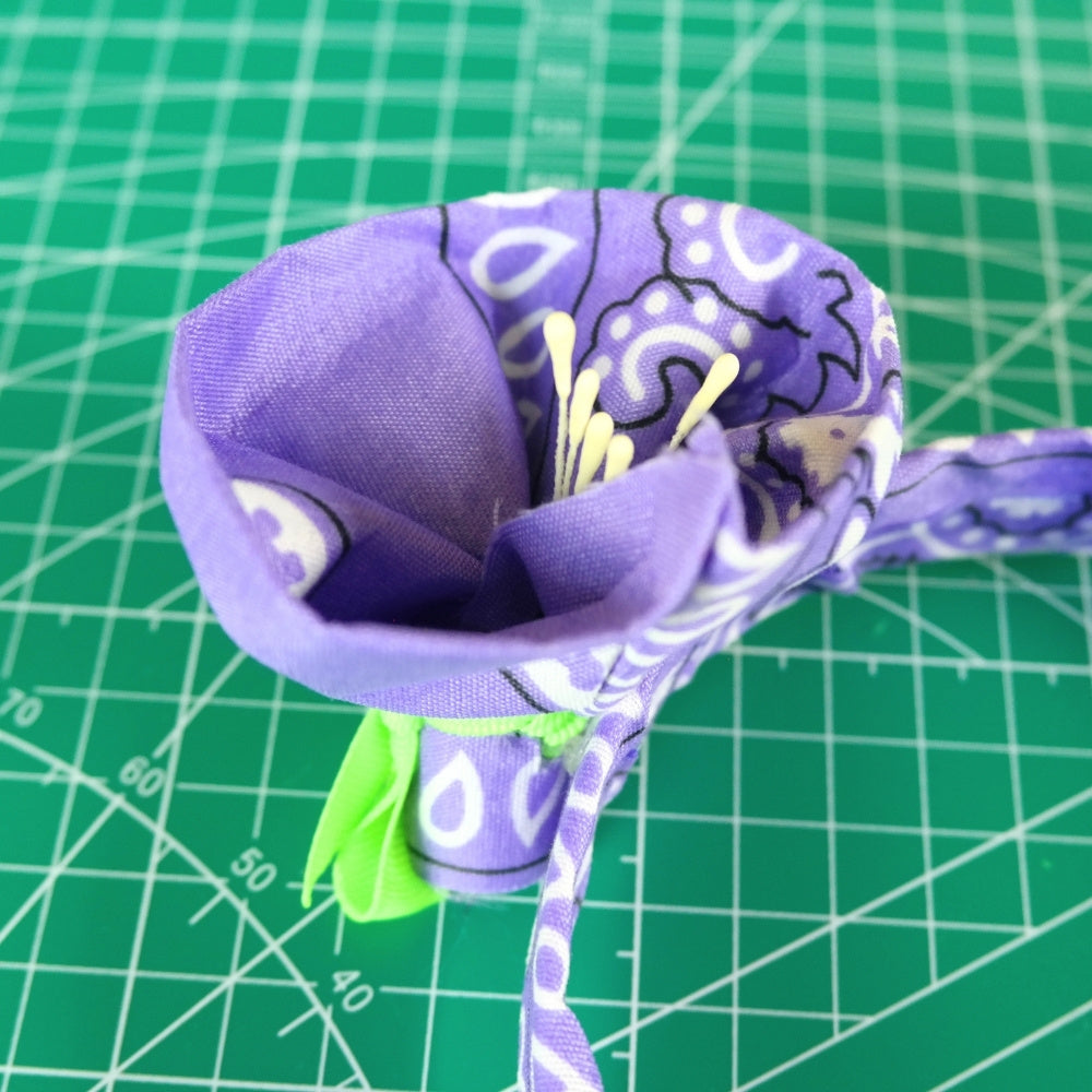 Zoomed-in photo of the bandana flower showing the flower petals and stamens, against a green crafting background. 