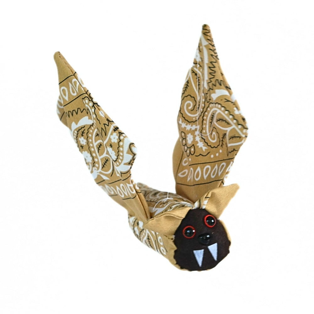 Three-quarter view of the finished Bandana Flying Bat with tan paisley wings raised and its dark felt face and white fangs visible.