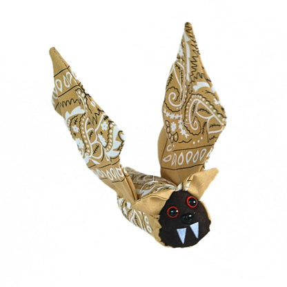 Three-quarter view of the finished Bandana Flying Bat with tan paisley wings raised and its dark felt face and white fangs visible.