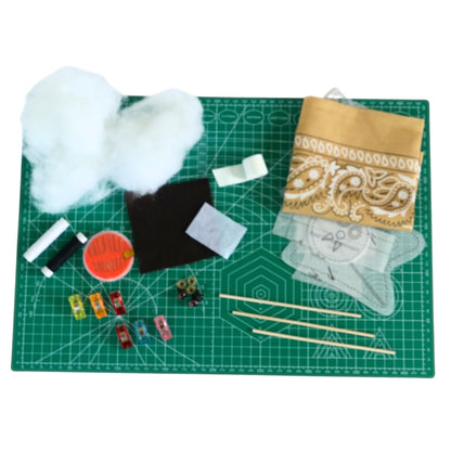 Bandana Flying Bat kit supplies arranged on a green cutting mat, including stuffing, fabric, patterns, felt, rods, sewing clips, thread, needle, eyes, and nose.