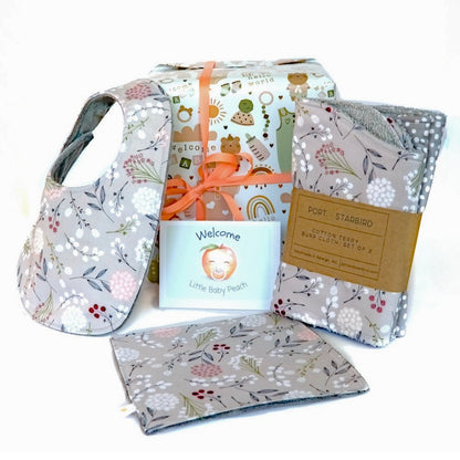Baby gift set with a bib, burp clothes, and crinkle toy on a white background