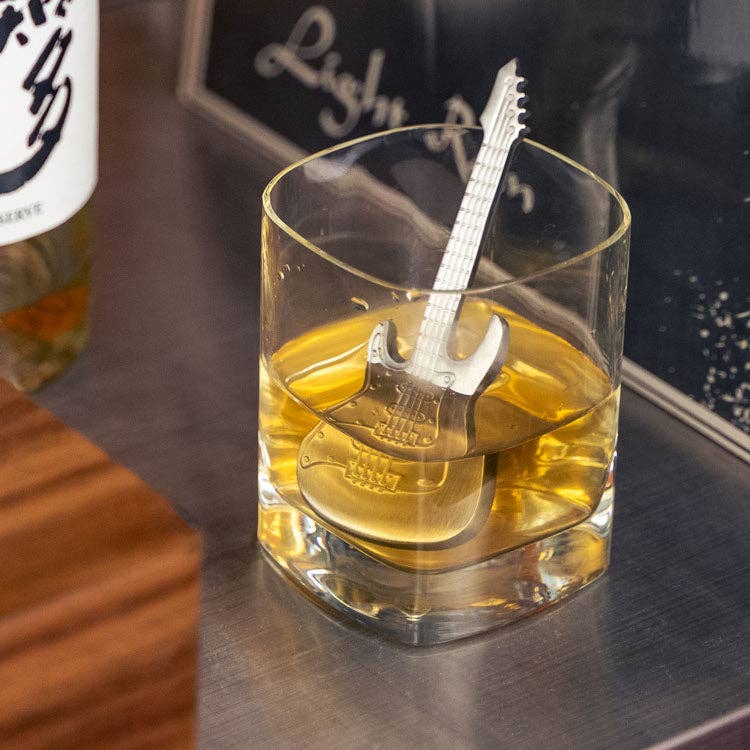 Electric Guitar Drink Chiller inside a chase glass with whiskey color drink on top of a table