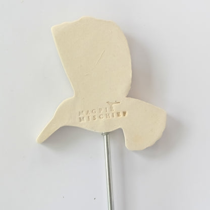 Back of decorative garden stake with a hummingbird design with the inscription "magpie mischief" on a white background