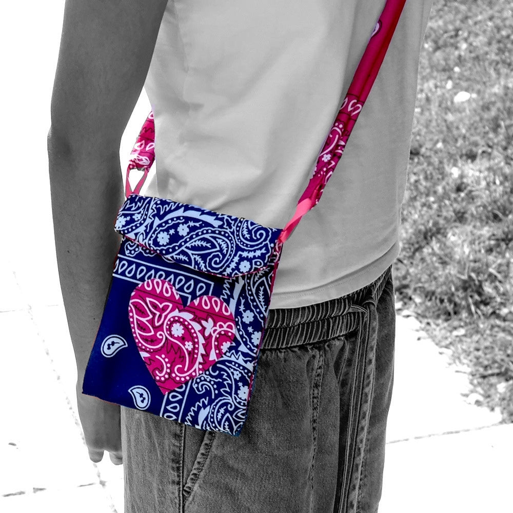 A girl wearing a small crossbody bag with a blue and pink paisley bandana pattern, shown in a black and white photo with the bag and its strap highlighted in color.