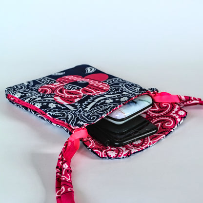 A bandana bag with a navy, pink, and white paisley pattern, shown open with a smartphone tucked inside. The sleeve features a matching pink and white paisley ribbon strap on a white background.