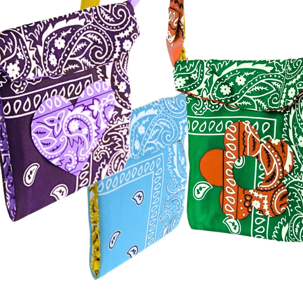 Three fabric crossbody bags with paisley bandana patterns in purple, light blue, and green, shown on a plain white background.