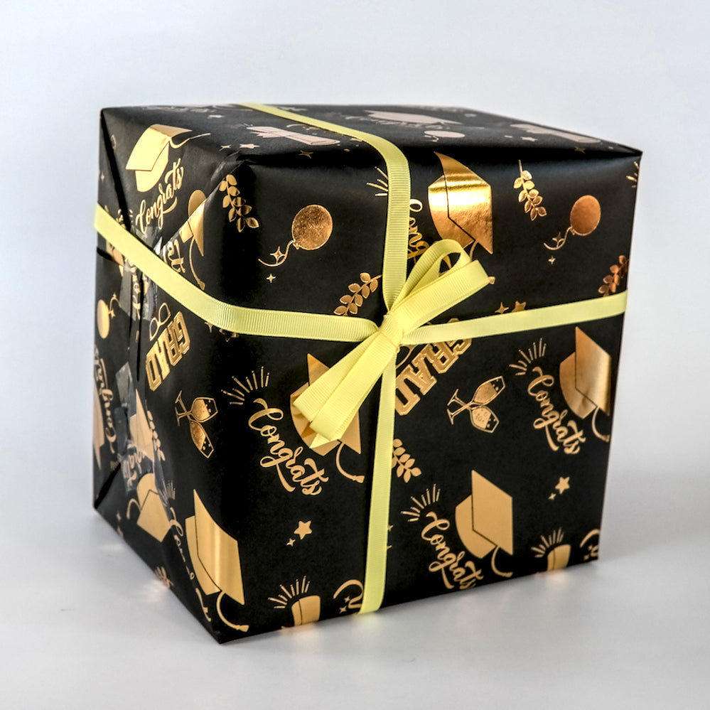 Black gift box with gold patterns and a yellow ribbon on a white background