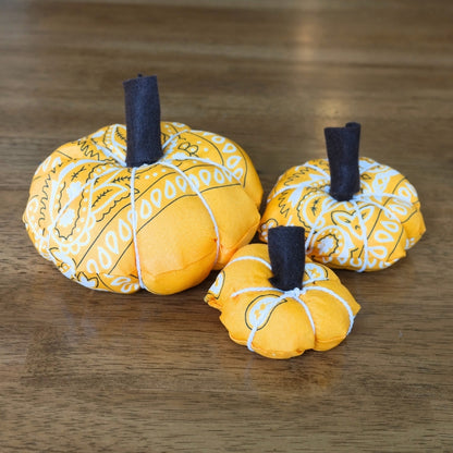 Handmade orange bandana pumpkin trio with felt stems and white cord displayed on a wooden table