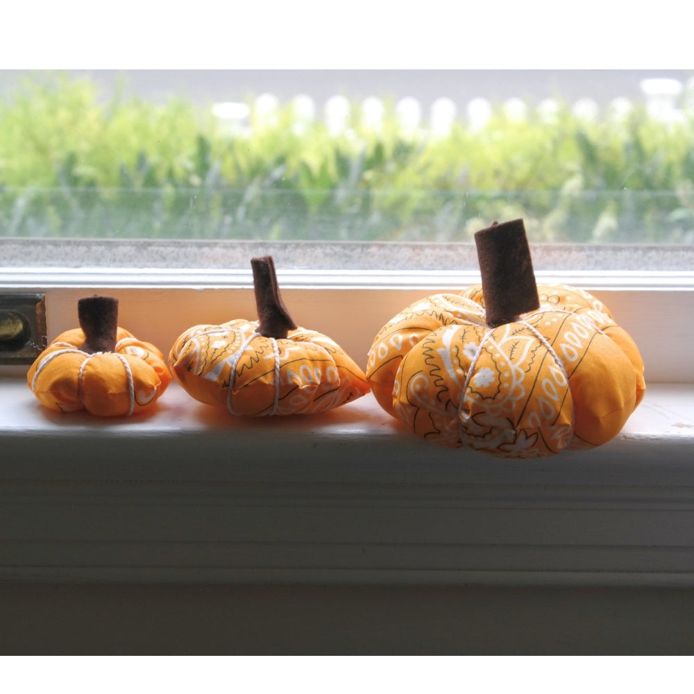 Three orange bandana pumpkins displayed on a windowsill as handmade fall home décor