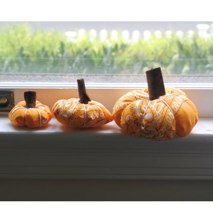Three orange bandana pumpkins displayed on a windowsill as handmade fall home décor