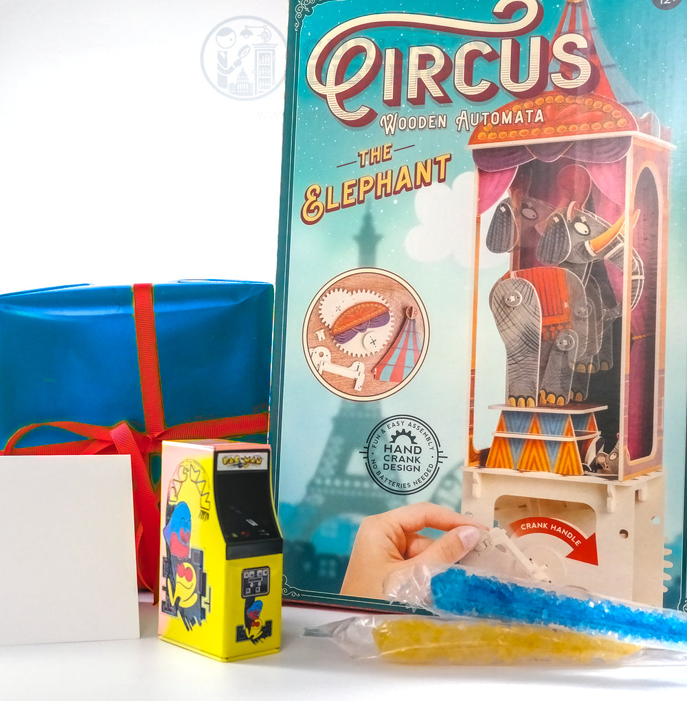 Circus-themed wooden automata packaging with a hand cranking mechanism, gift box, and small toy.