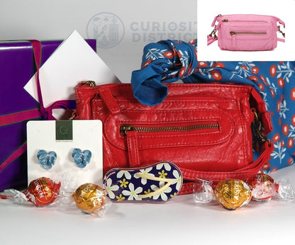 Red handbag with accessories and candies on a white surface