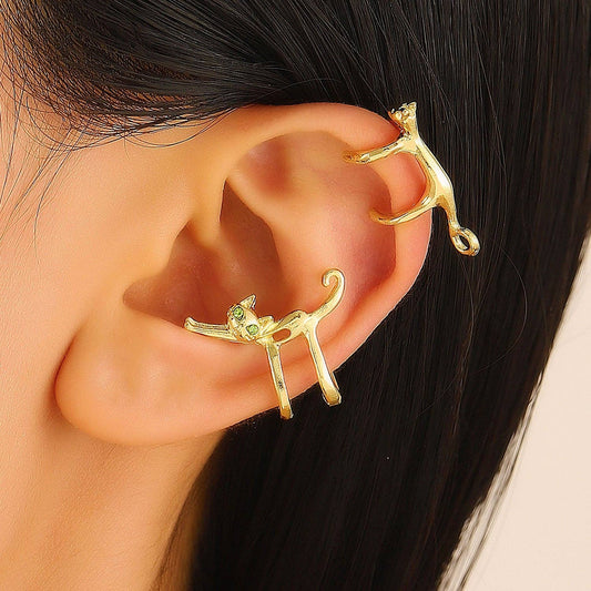 Gold cat-shaped ear cuffs worn by a person with black hair.