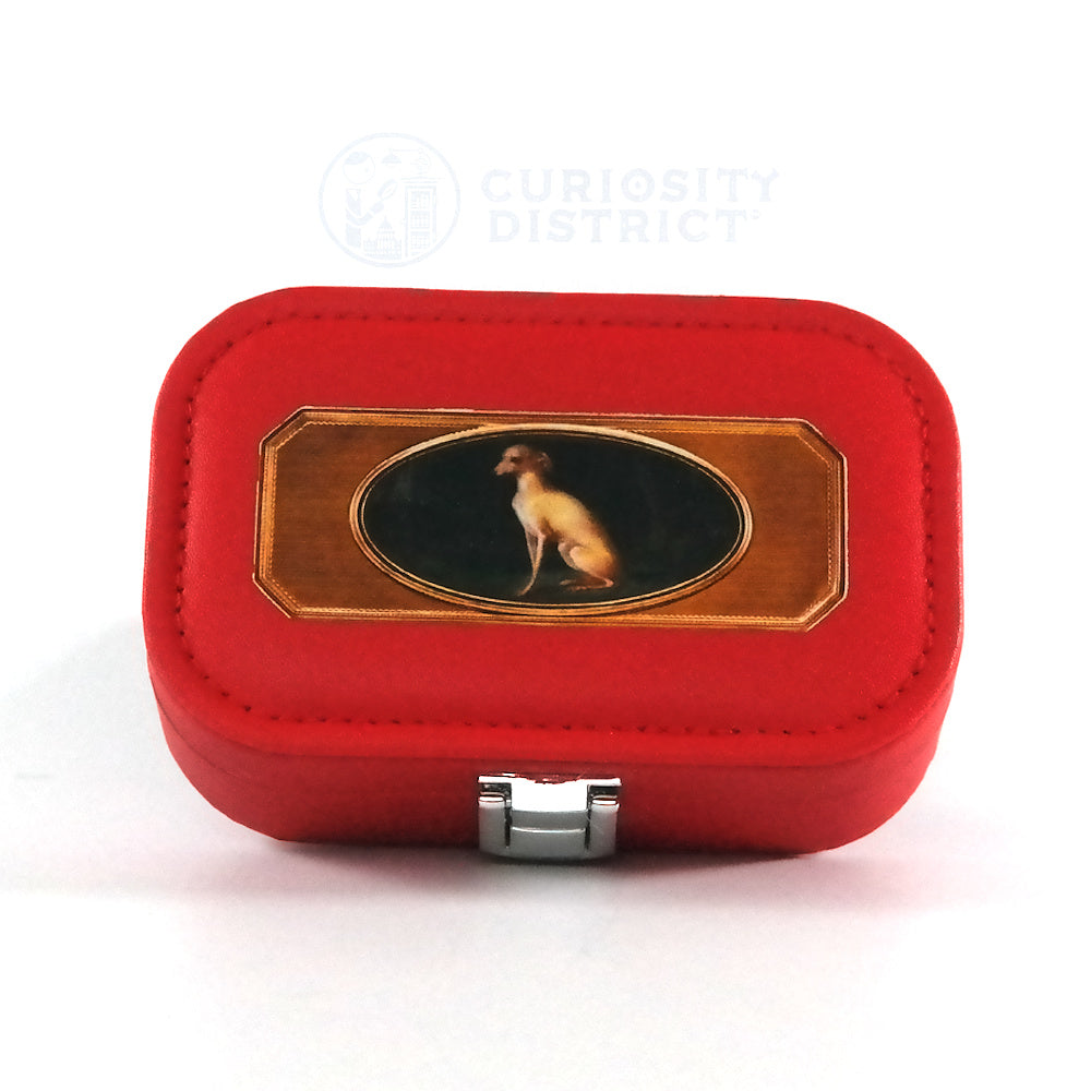 Miniature red jewelry box with a button closure and the portrait of a whippet, pictured from the top. 